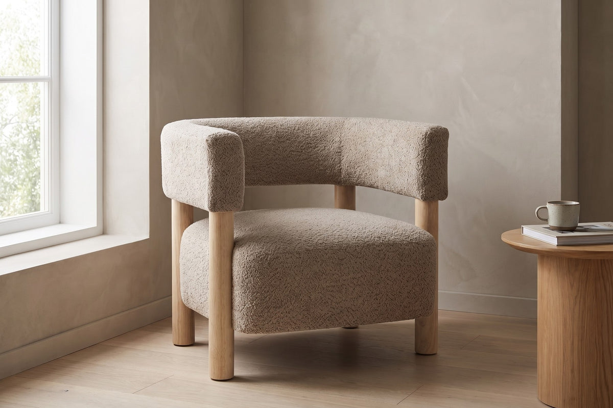Agathe light camel bouclé barrel accent chair with natural wood legs in a sunny corner by a large window