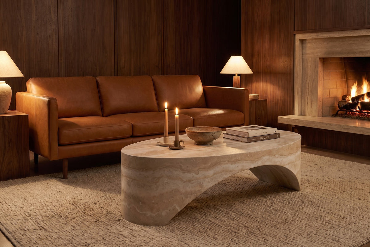 Evening. In front of a cognac leather sofa, the travertine look turns warm in lamplight.