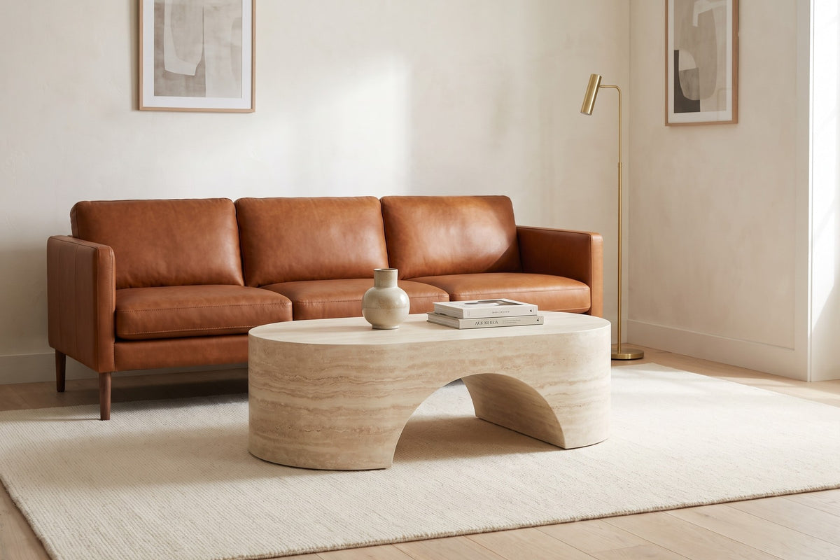 Against warm white walls and framed prints, the oval softens a square-armed sofa.