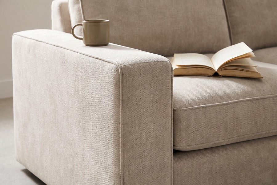 Annecy Modular L-Shaped Sectional: close-up of the wide flat-topped box arm with a ceramic cup and a book resting on it, chenille texture visible