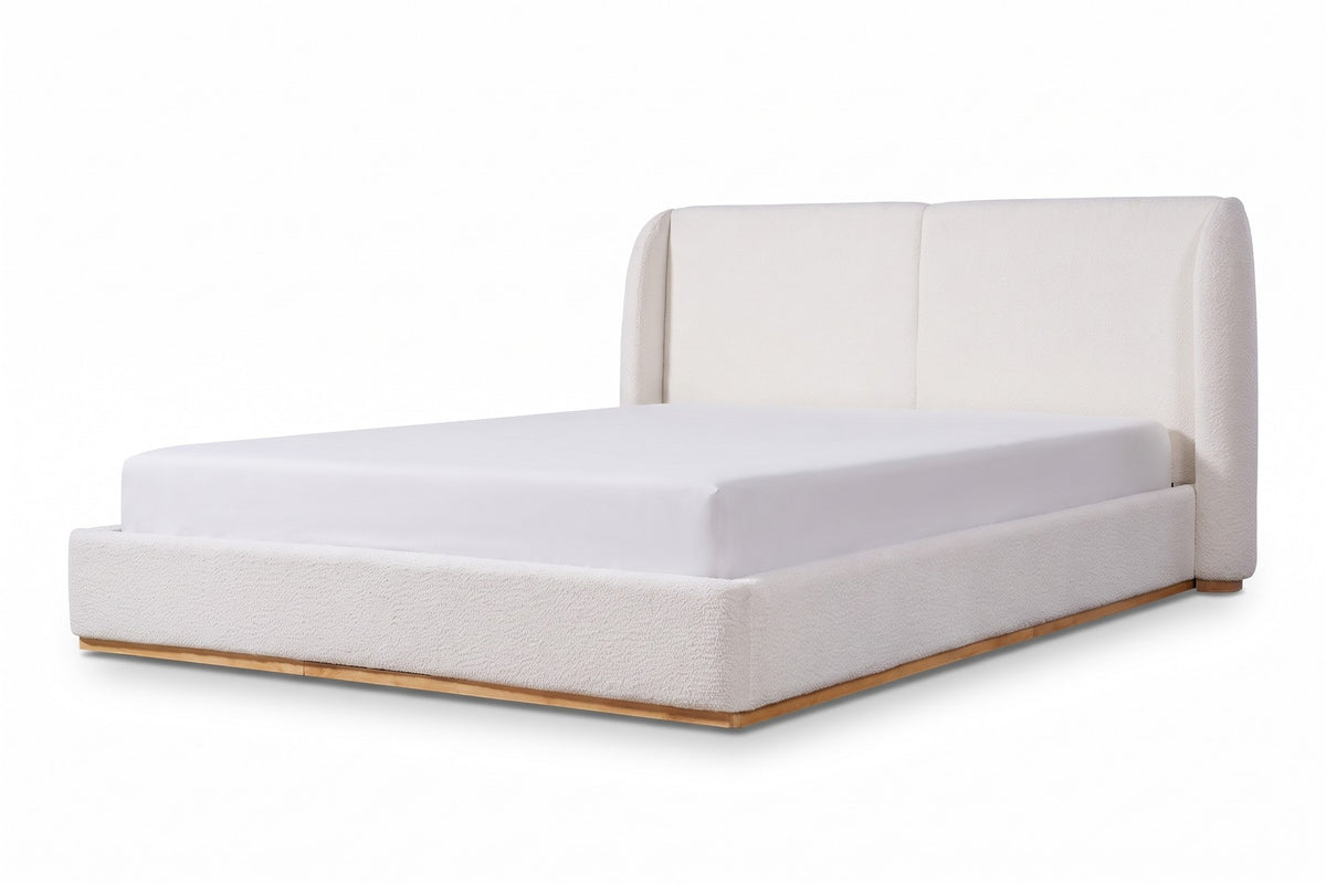 Apolline white bouclé platform bed with a wingback headboard, low three-quarter side view showing the profile of one rounded headboard wing and the full length of the low rail on a white background