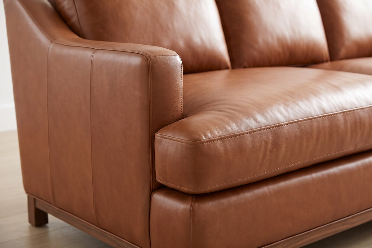 Arcachon Cognac Deep Leather Sofa: close-up of a slim cognac leather arm sloping down toward the front, where it meets the deep welted seat cushion