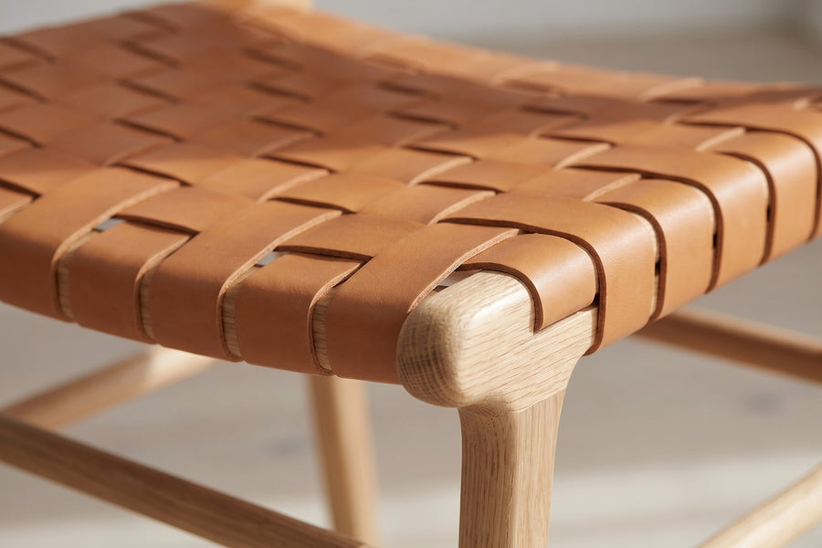 Arles Woven Leather Dining Chair: close-up of the open basket weave of flat tan leather straps on the seat, where they wrap around the oak seat rail