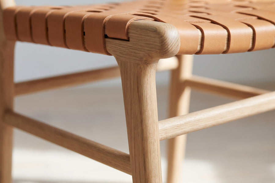 Arles Woven Leather Dining Chair: close-up of the joint where a tapered oak leg meets a side stretcher, natural oak grain visible