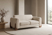 Auteuil almond bouclé loveseat with sculpted walnut-finish feet in a calm, daylit living room