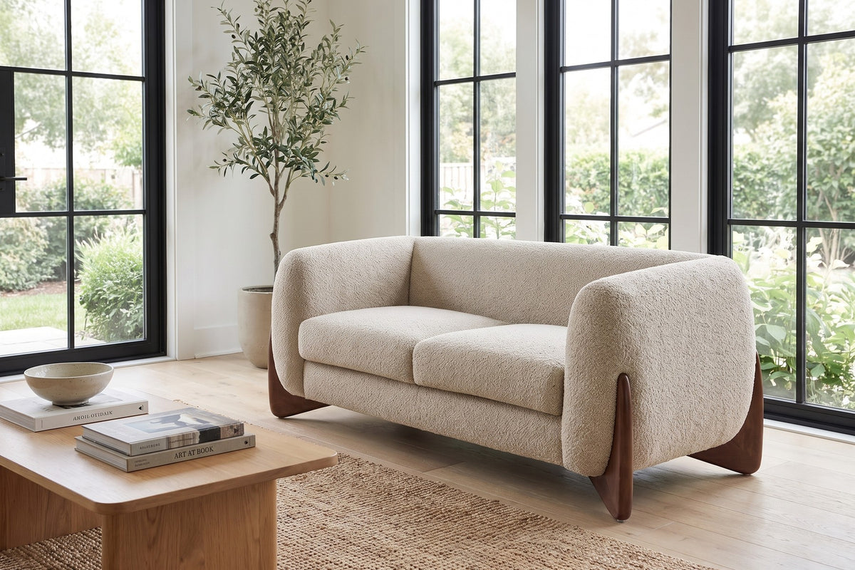 Auteuil almond bouclé loveseat with sculpted walnut-finish feet in a bright sunroom-style living room