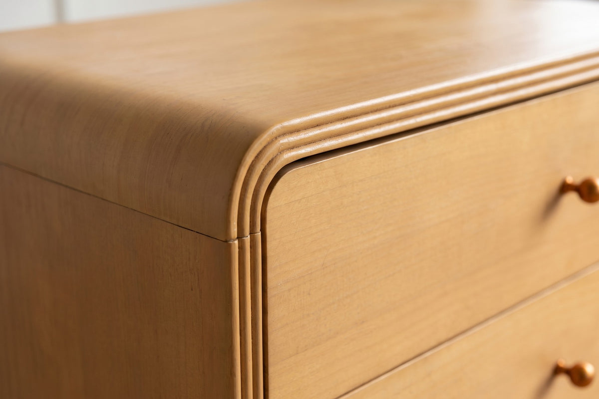 Close-up of a rounded front corner, showing the grooved border around the drawers and the curved top edge (Belleville)