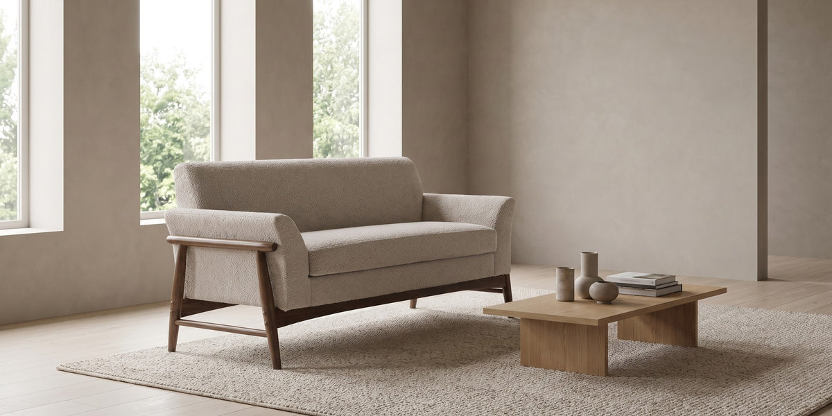 Bercy almond bouclé loveseat with flared arms and a walnut-finish frame in a wide, calm living room