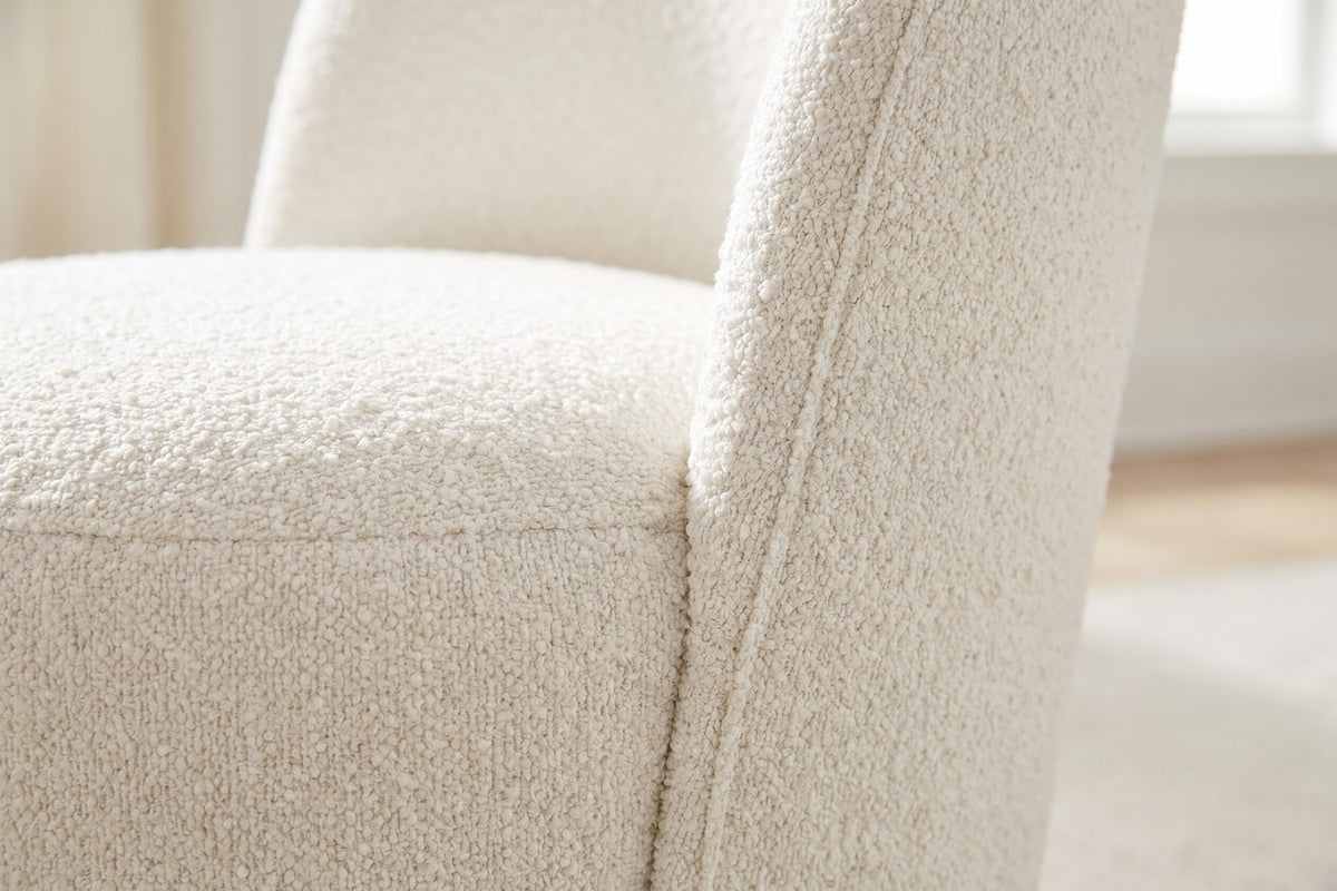 Close-up of the curly ivory bouclé where the curved back meets the round drum seat (Bérénice)