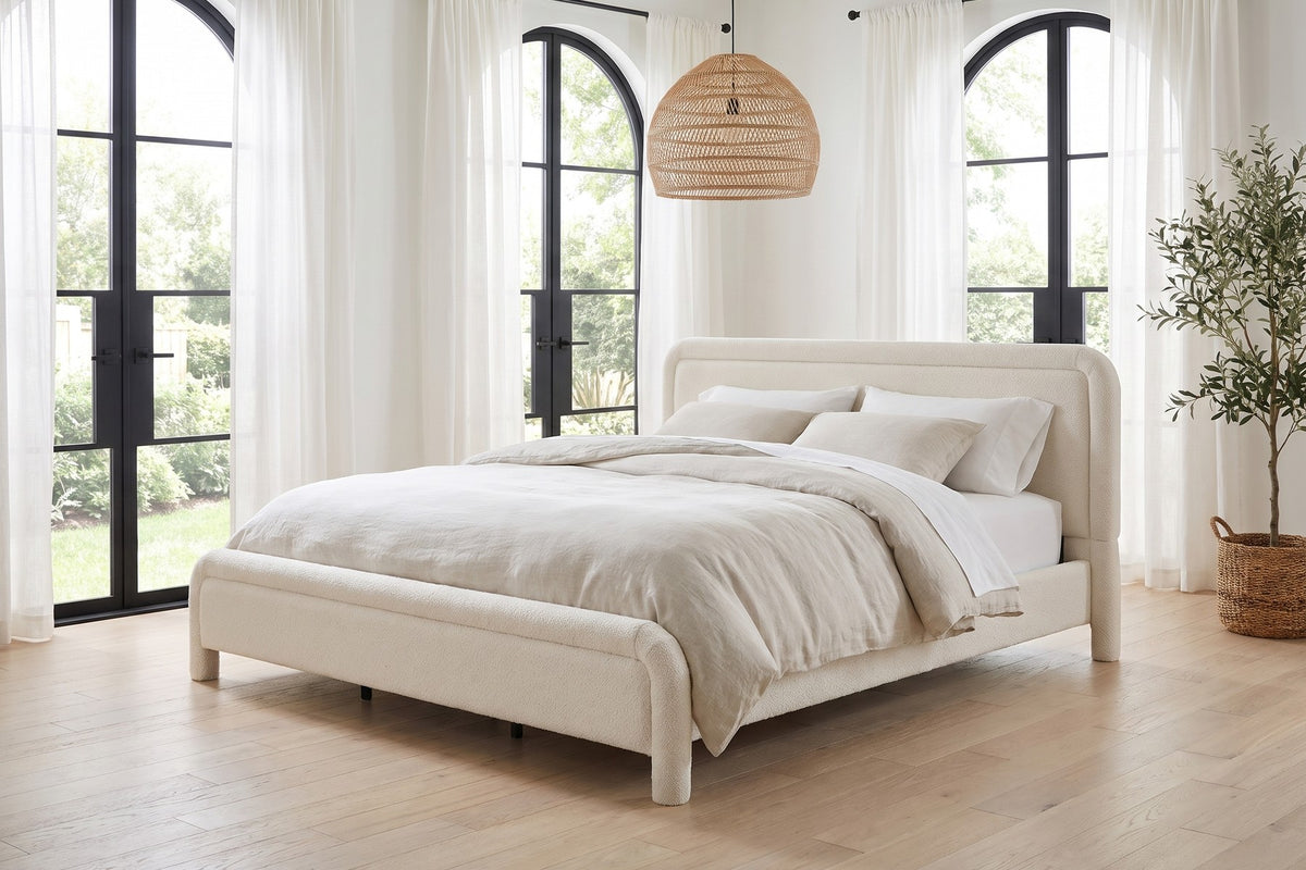 Daylight. Under tall arched windows, the white bouclé brightens the whole room.