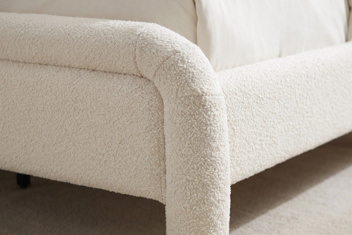 Close-up of one foot corner where the rolled white bouclé frame curves down into a thick rounded leg (Capucine)
