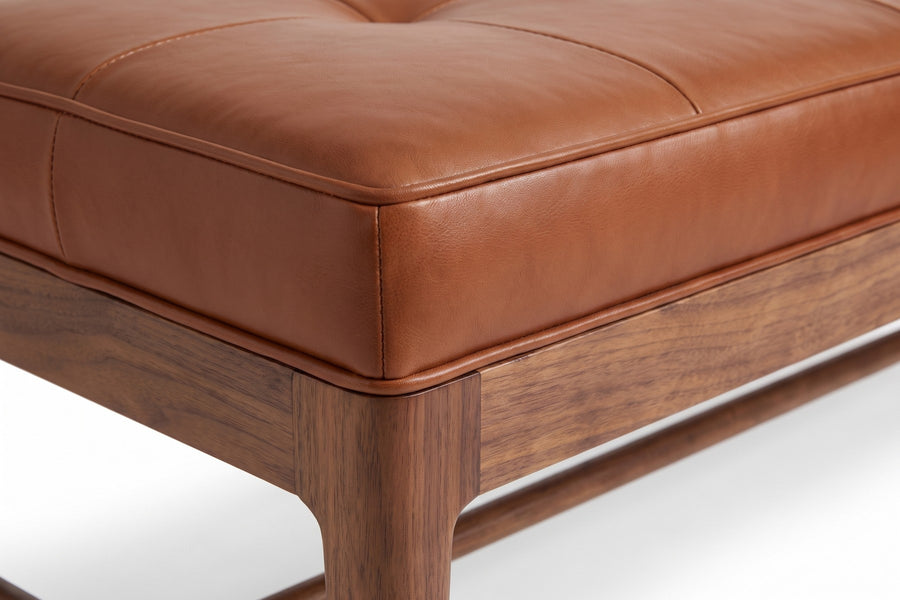 Carnac Cognac Leather and Walnut Bench: close-up of the cognac leather top's stitched grid and welted edge where it meets the walnut rail