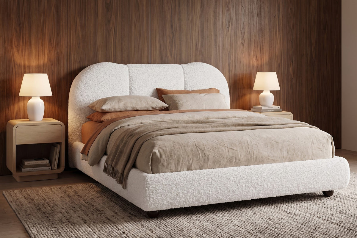 Celeste white bouclé platform bed with a cloud headboard in a warm walnut-panelled bedroom in the evening
