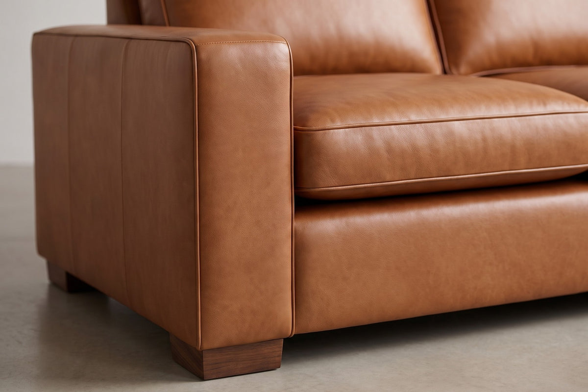 Deauville Cognac Leather Sofa: close-up of the wide flat-topped track arm meeting a seat cushion, showing the cognac leather grain, its soft sheen and the fine welted cushion edge