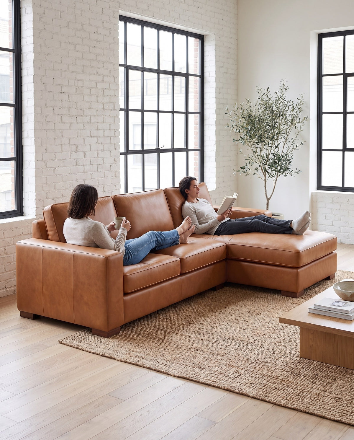 Two people stretched out on the Deauville cognac leather chaise sectional (concept image)