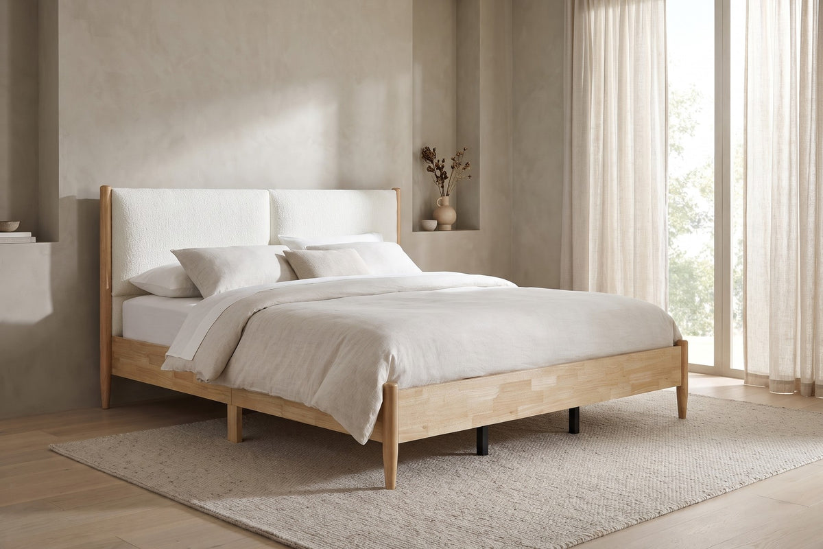 By sheer-curtained windows, the natural wood frame and white headboard keep the room light.