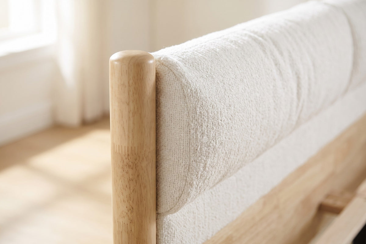 Close-up of one round wooden headboard post with its rounded top beside the textured white headboard cushion (Delphine)