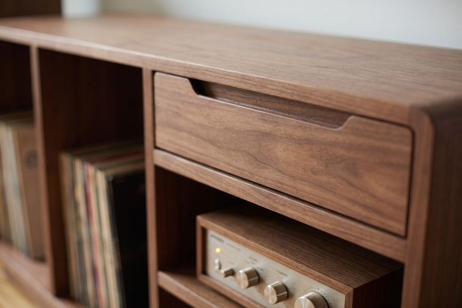 Dinard Walnut Record Cabinet: close-up of the drawer's routed finger-pull groove and the open shelf below it holding a small amplifier, walnut grain visible