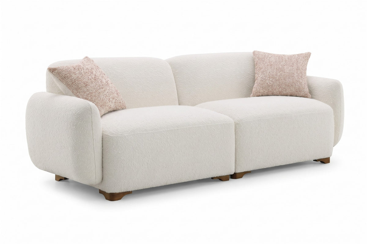 Estelle cream bouclé rounded sofa with two flecked pillows, three-quarter view on a white background