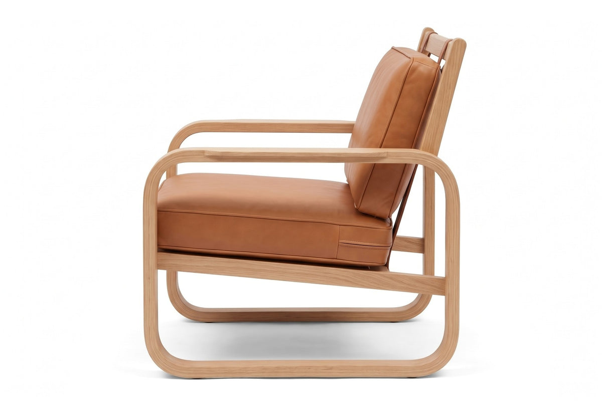 Étretat Bentwood Oak and Cognac Leather Lounge Chair, view from the left side, slightly to the front, showing the bent oak loop and the reclined back cushion