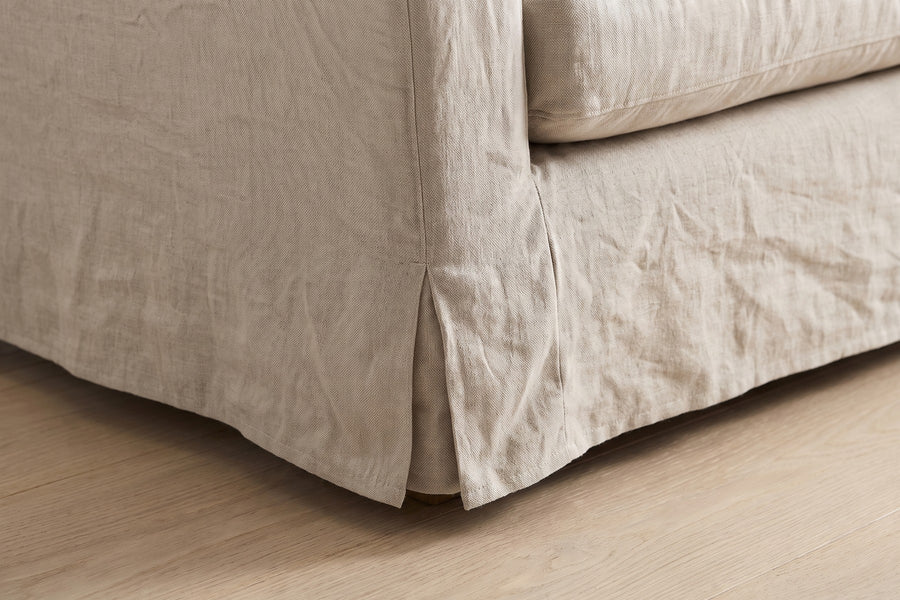 Germain 90" Slipcovered Linen-Blend Sofa: close-up of the short tailored skirt at the bottom corner of the sofa, just above a pale oak floor