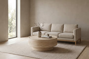 Haussmann 31.5" round drum coffee table with a travertine-look finish in a calm, daylit living room in front of a sofa