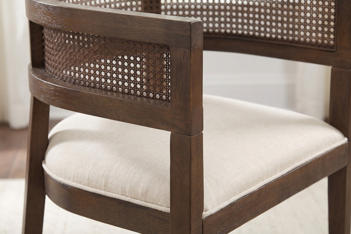 Close-up of the arm end where the caned rail meets the square front leg, above the piped beige seat (Ines)