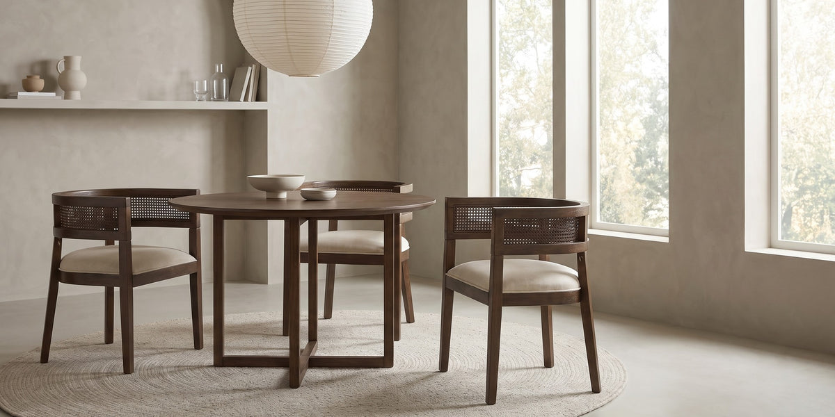 Ines cane barrel dining chair with a walnut-finish frame and beige seat in a wide, calm dining room