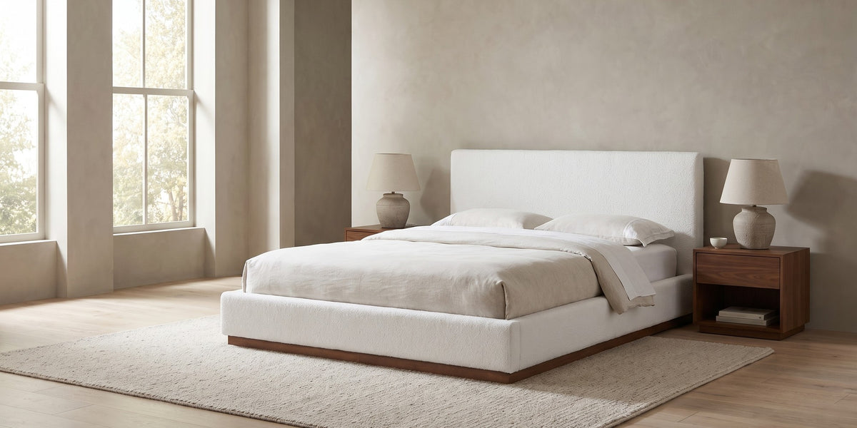 Jeanne white upholstered bed with a brown rubberwood base in a wide, calm bedroom