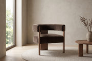 Juliette dark brown velvet barrel accent chair with a walnut-finish frame in a calm, daylit living room