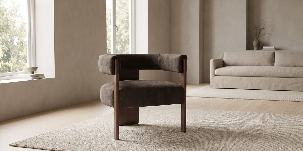 Juliette dark brown velvet barrel accent chair with a walnut-finish frame in a wide, calm living room