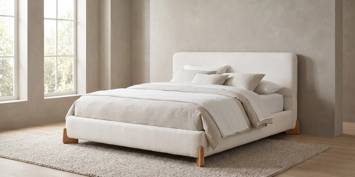 Léonie white bouclé king platform bed with natural wood corner feet in a wide room view