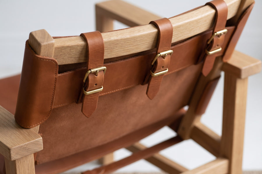 Lourmarin Cognac Leather Sling Chair on Natural Oak: close-up of the back of the chair where the cognac leather back sling wraps round the oak top rail and is fastened with three leather straps and small solid brass buckles