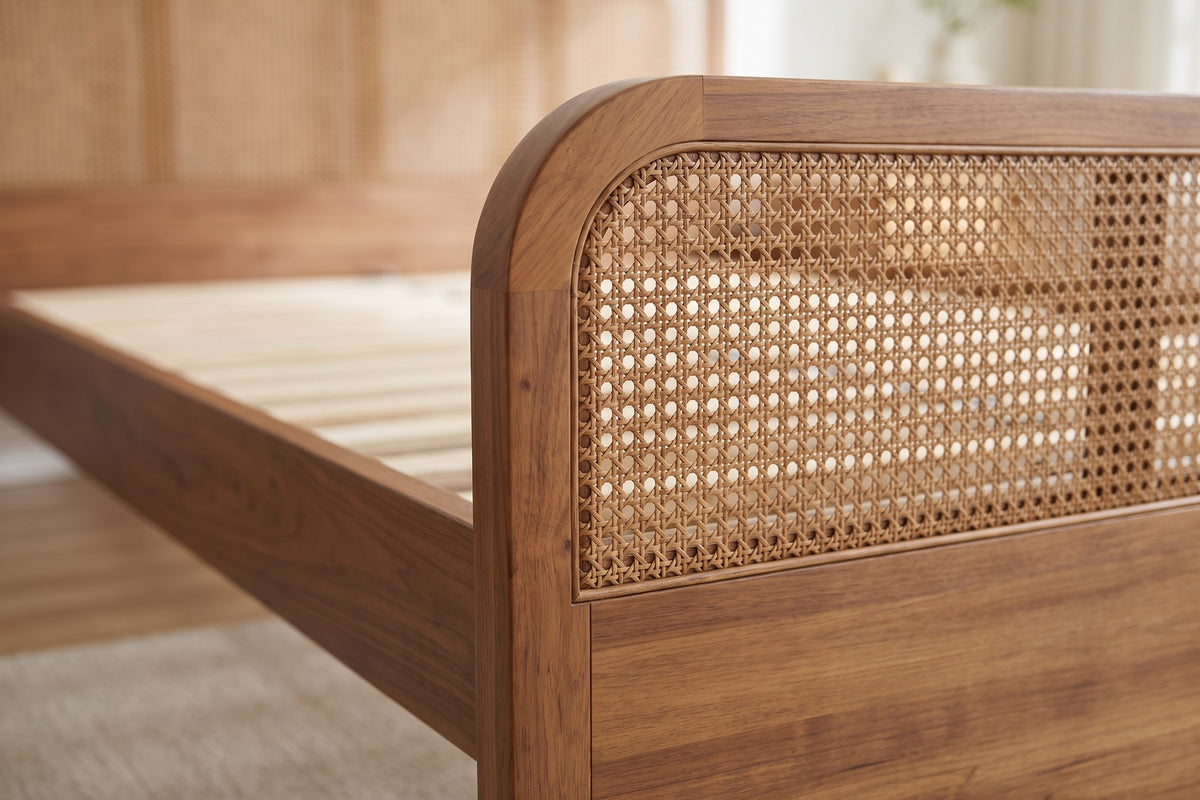 Close-up of the woven cane band and its rounded corner on top of the walnut-finish wood panel footboard (Malo)