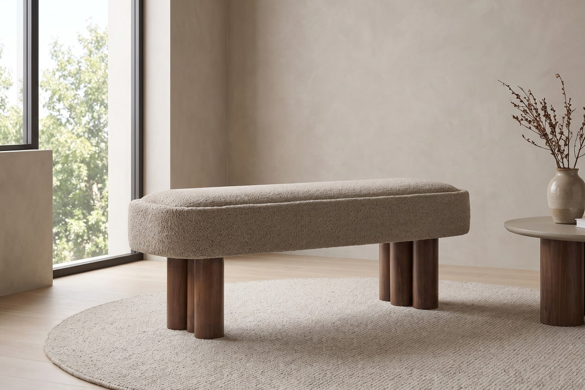 By a tall window. On its own, the bench shows off its two clusters of round legs.