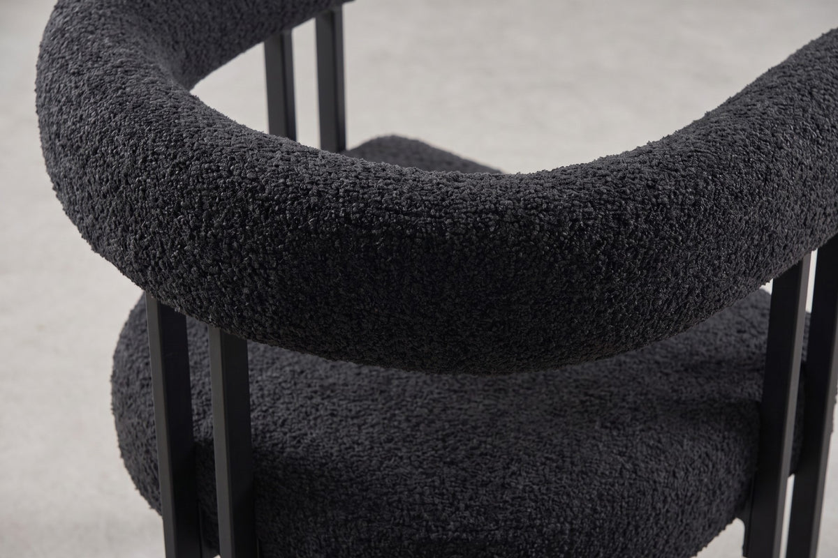 Close-up of the curly charcoal-black boucle on the rounded backrest where it curves into the arm (Mathilde)