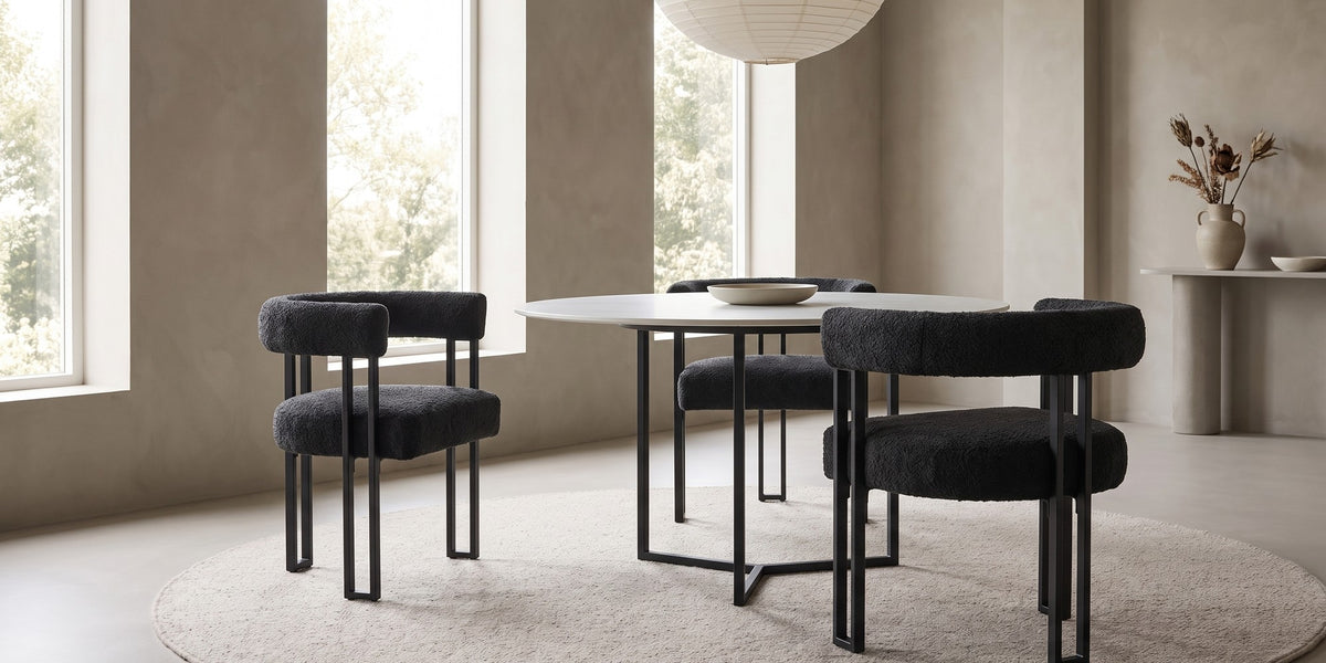 Mathilde black bouclé barrel dining armchair with black metal legs in a wide, calm dining room