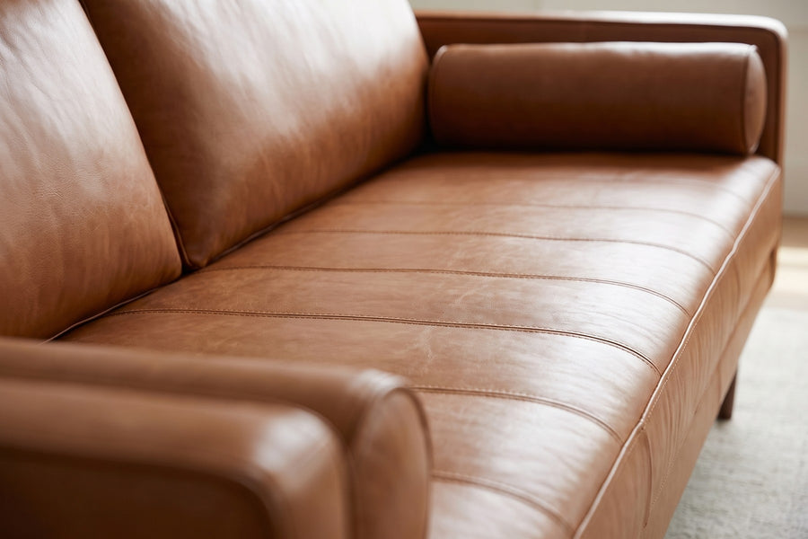 Menton 88" Cognac Leather Bench-Seat Sofa: close-up of the cognac leather bench seat, showing the fine stitched channels, the leather grain and its soft sheen