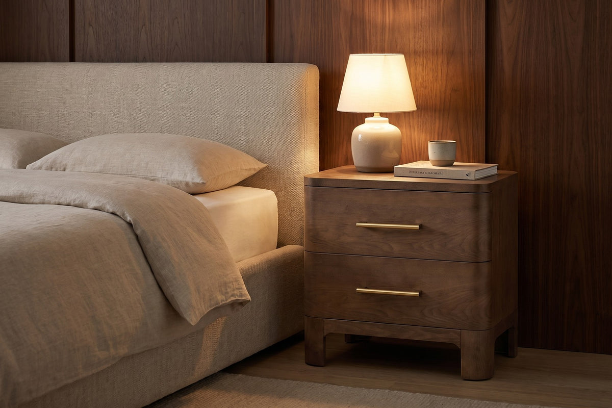 Lamp on. A book and a cup on top, and the rounded corners soft in the low light.