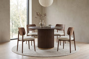 Odeon 47-inch round walnut-finish dining table with a slatted drum pedestal in a calm, daylit dining room