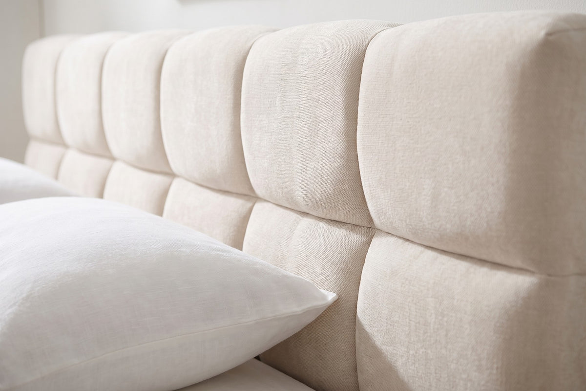 Close-up of the headboard's square chenille tufts in two rows, seen slightly from one side, with the edge of a white pillow (Odette)