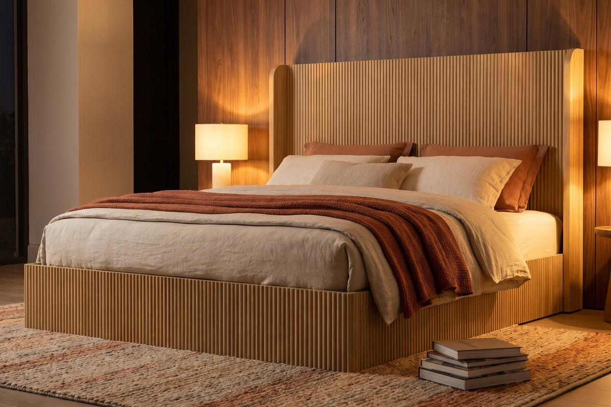 Evening. In lamplight, the tall wingback headboard turns a warm honey tone.