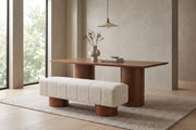 Pigalle cream bouclé channel bench with walnut-tone drum legs in a calm, daylit dining room