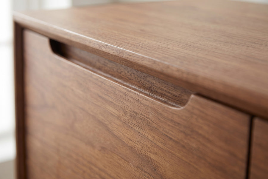 Quimper Walnut Sideboard: close-up of the finger-pull groove routed under the top's front edge, above a walnut door, showing the grain