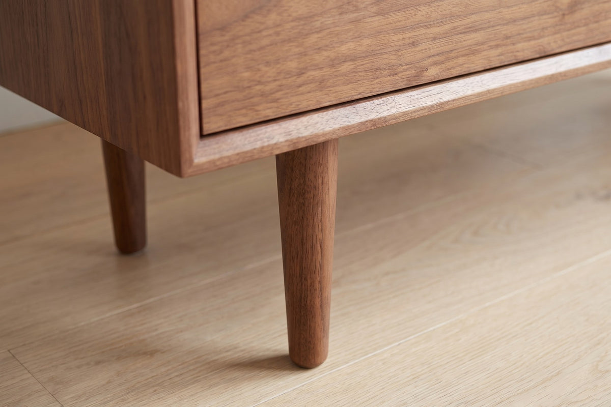 Quimper Walnut Sideboard: close-up of a round tapered walnut leg meeting the underside of the case, on a pale oak floor