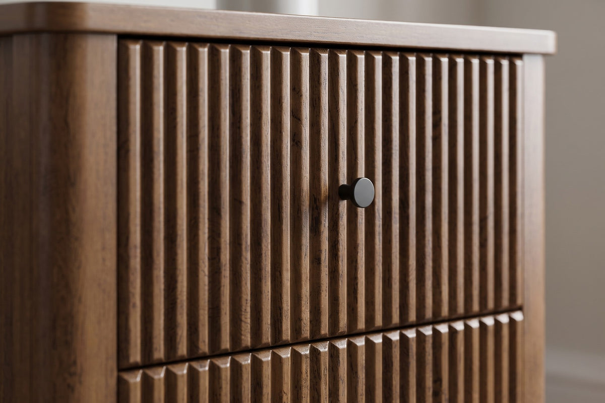 Close-up of the vertical flutes on a walnut-finish drawer front with one small round black knob (Raspail)