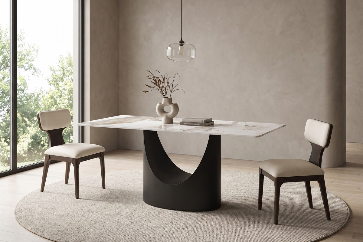 Rivoli 63-inch white sintered stone dining table with a black crescent base and beige chenille chairs in a calm daylit dining room