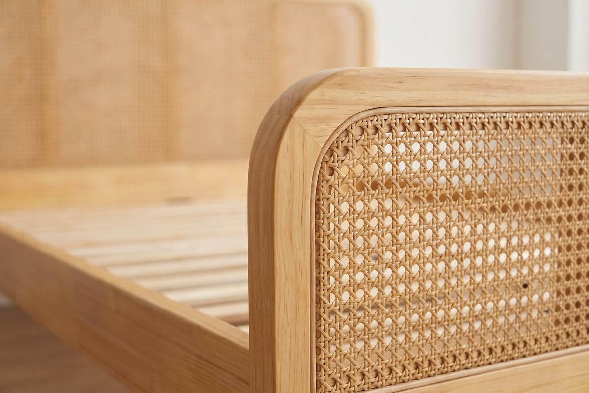 Close-up of the woven cane panels in the headboard where they meet the rounded top corner of the natural wood frame (Romy)