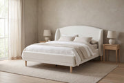 Sabine white bouclé bed with a wingback headboard and tapered wood legs in a calm, daylit bedroom
