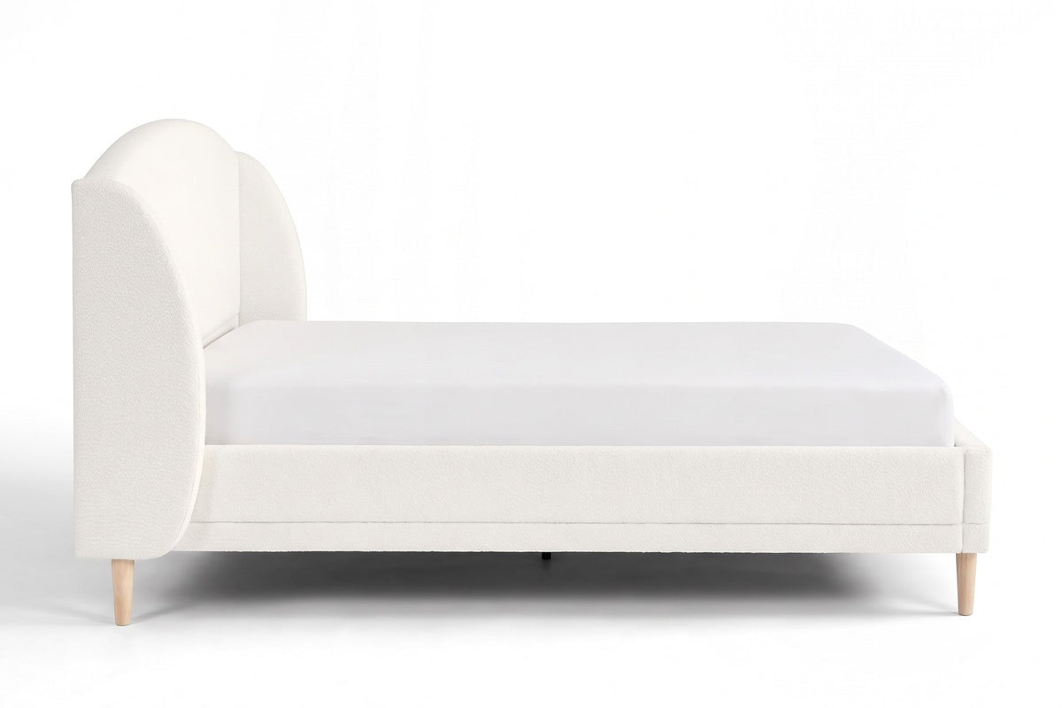 Sabine white bouclé bed with a wingback headboard and tapered wood legs, straight side view at mattress height, showing the profile of the wings and the tapered legs on a white background